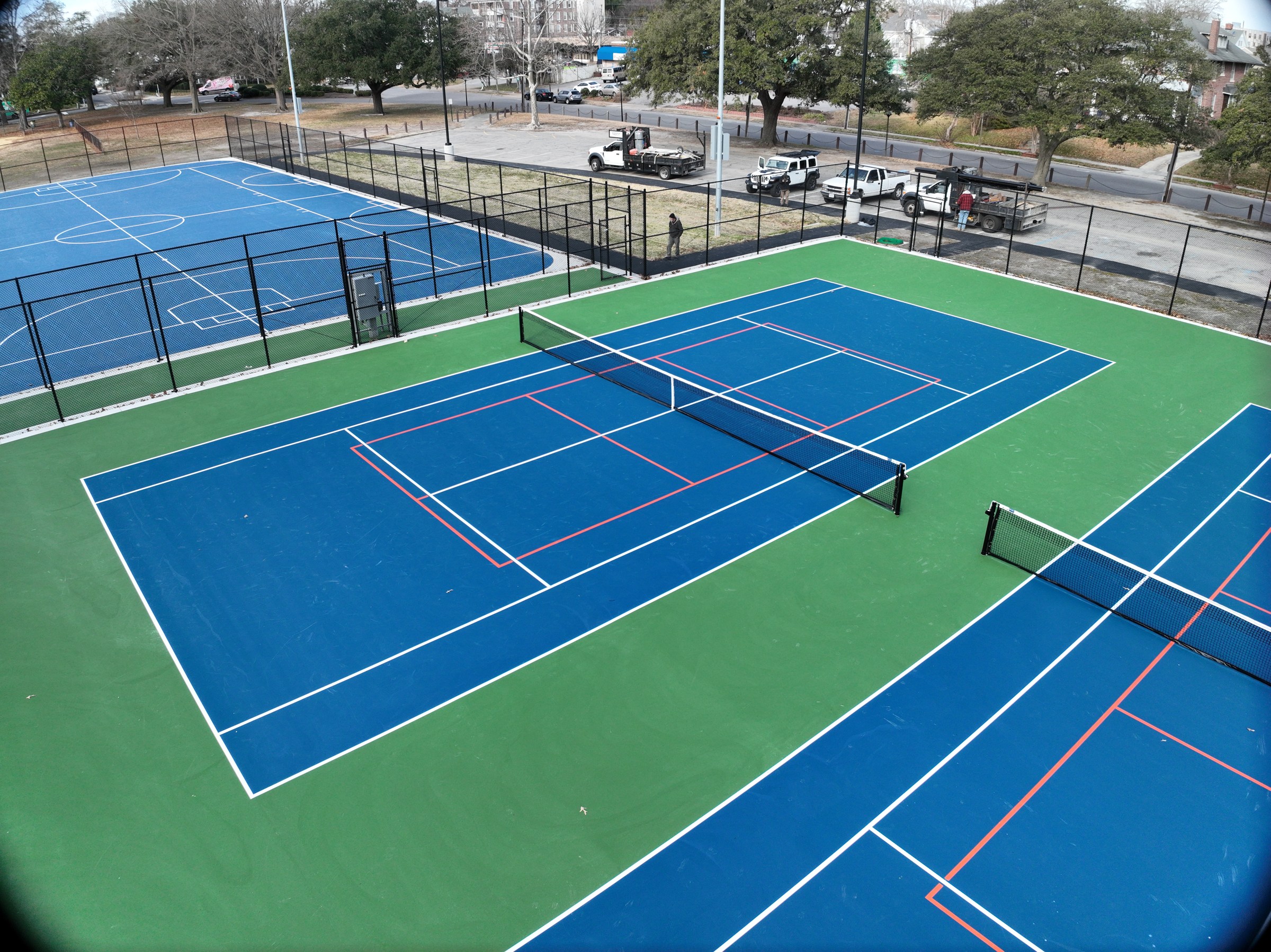 Court coatings, line markings, nets, and fencing complete the tennis playing areas.